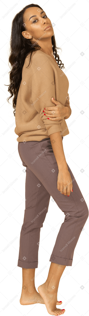 Вид сбоку скучающей молодой темнокожей женщины, держащей руку, глядя в камеру