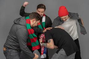 Close-up of four fighting male football fans