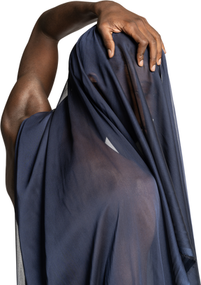 Vista posterior de un joven afro cubierto con un chal azul oscuro tocando su cabeza