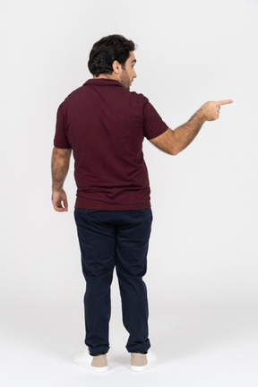 Vue arrière d'un homme en vêtements décontractés pointant du doigt