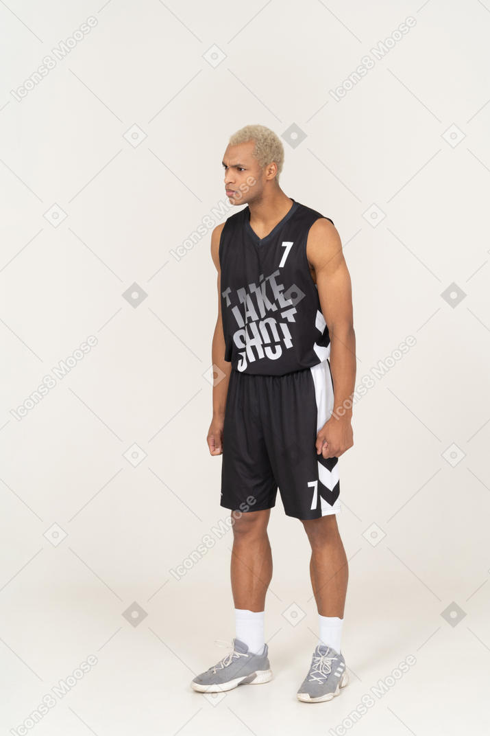Vista di tre quarti di un giovane giocatore di basket maschio arrabbiato che stringe i pugni