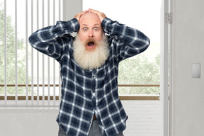 Shocked elderly man holding his head