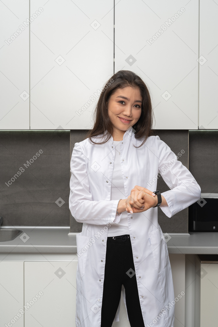 Front view of a smiling female doctor checking the time