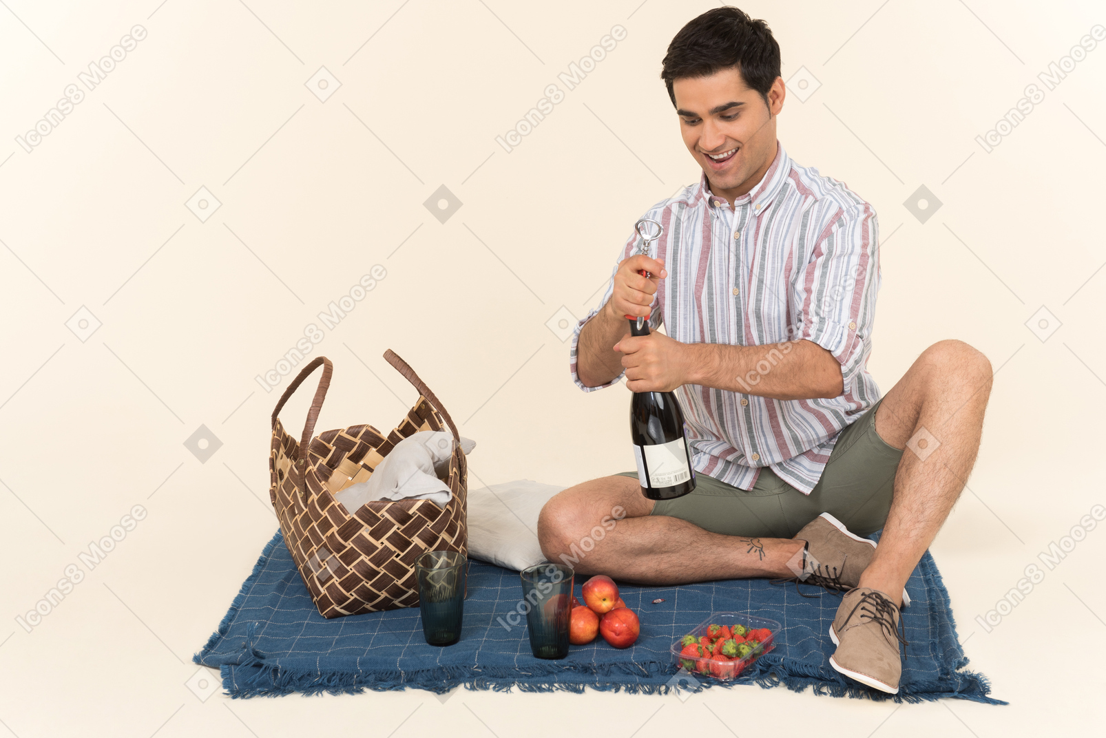 Junger kaukasischer mann, der auf der decke sitzt und flasche wein öffnet