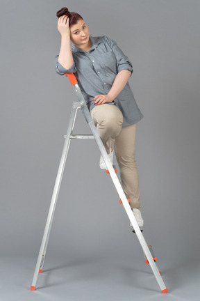 Woman sitting on stepladder and holding her head