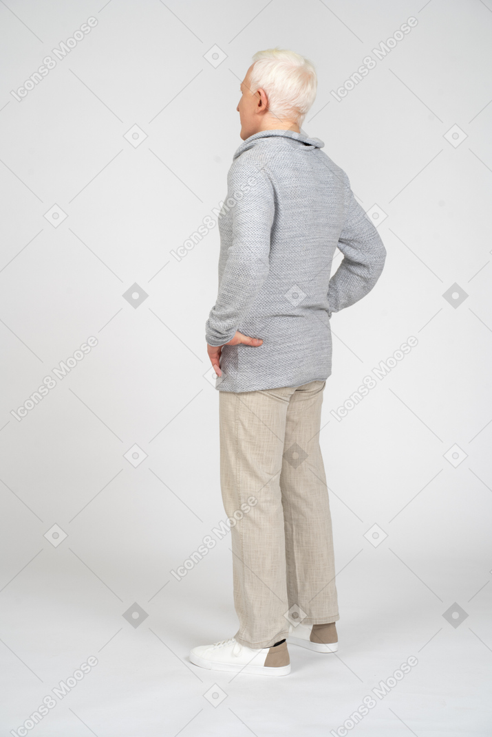Vista posteriore di un uomo in piedi con le mani sui fianchi