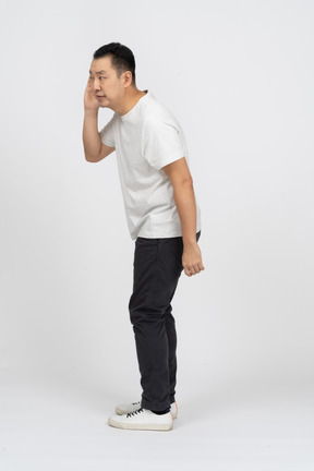 Side view of a man in casual clothes eavsdropping