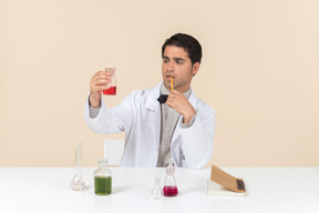 Male scientist holding bulb and sitting at the table