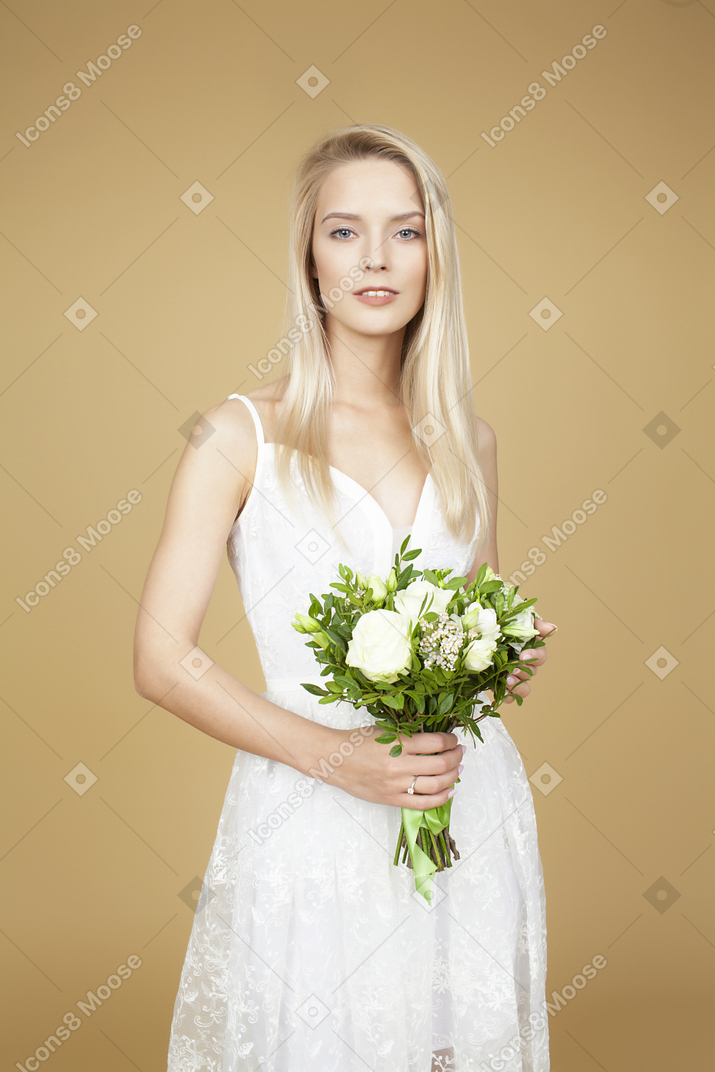 Красивая невеста держит букет и позирует для фото