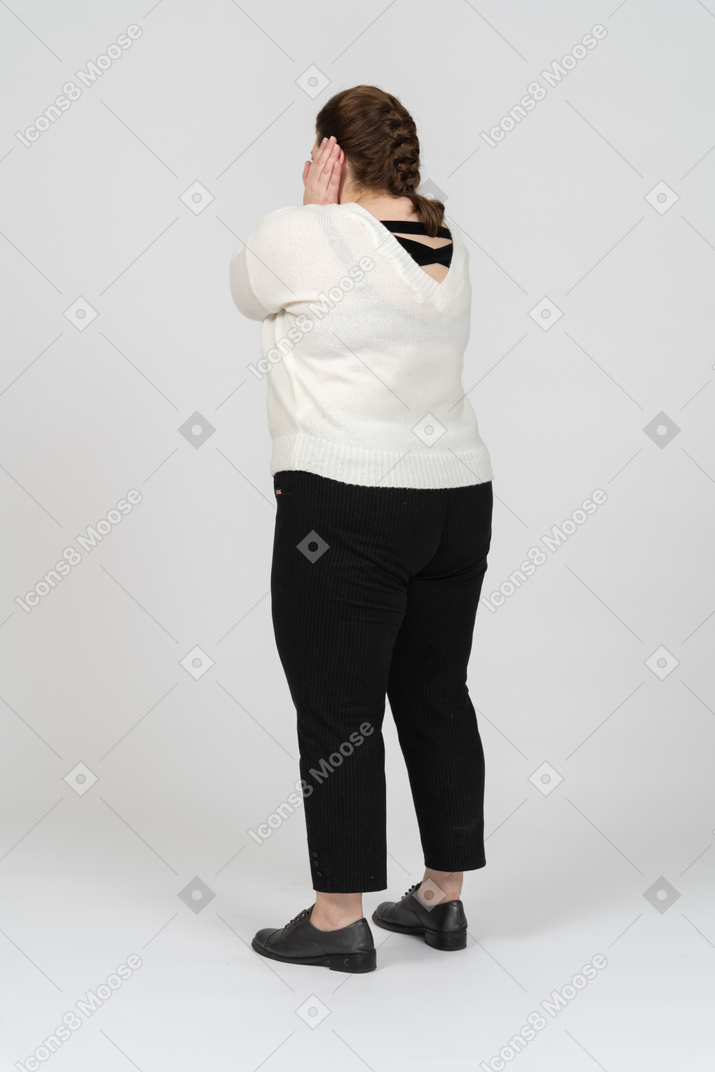 Plus size woman in white sweater closing ears