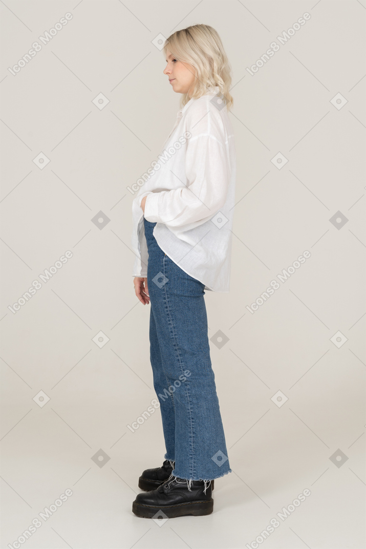 Vista lateral de uma mulher loira em roupas casuais colocando a mão no bolso