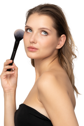Side view of a sensual young woman holding a make-up brush & looking at camera