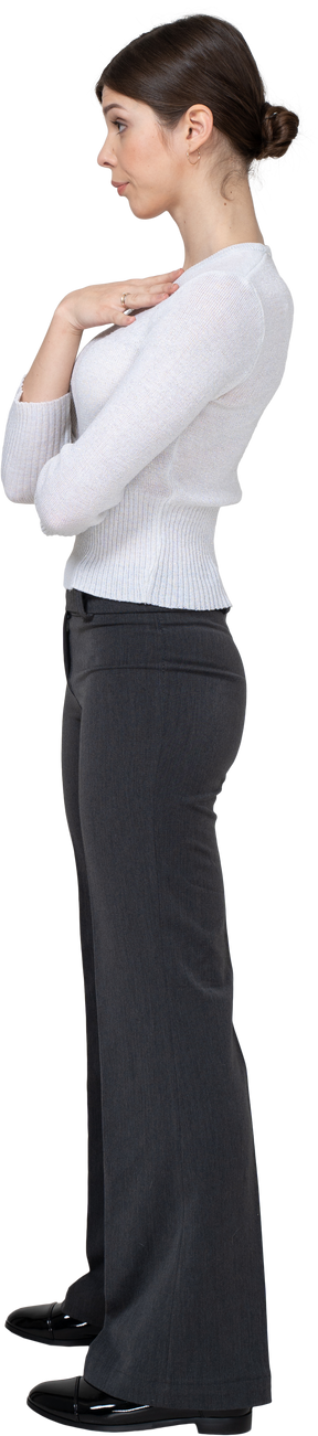 Vista lateral de una mujer joven mandona en ropa de oficina tocando el pecho