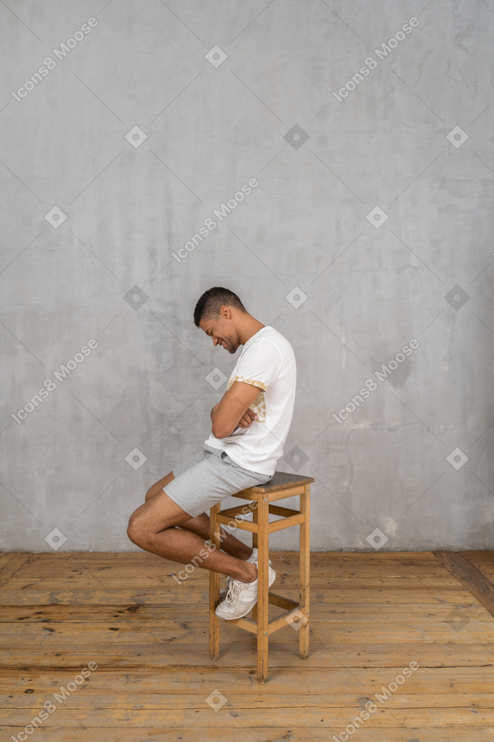 Vista lateral do homem sentado na cadeira e rindo