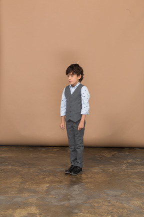 Vista frontal de un niño en traje gris parado