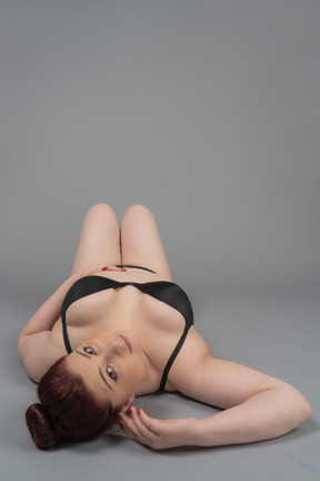 Sensual plus size female in black lingerie lying on the floor