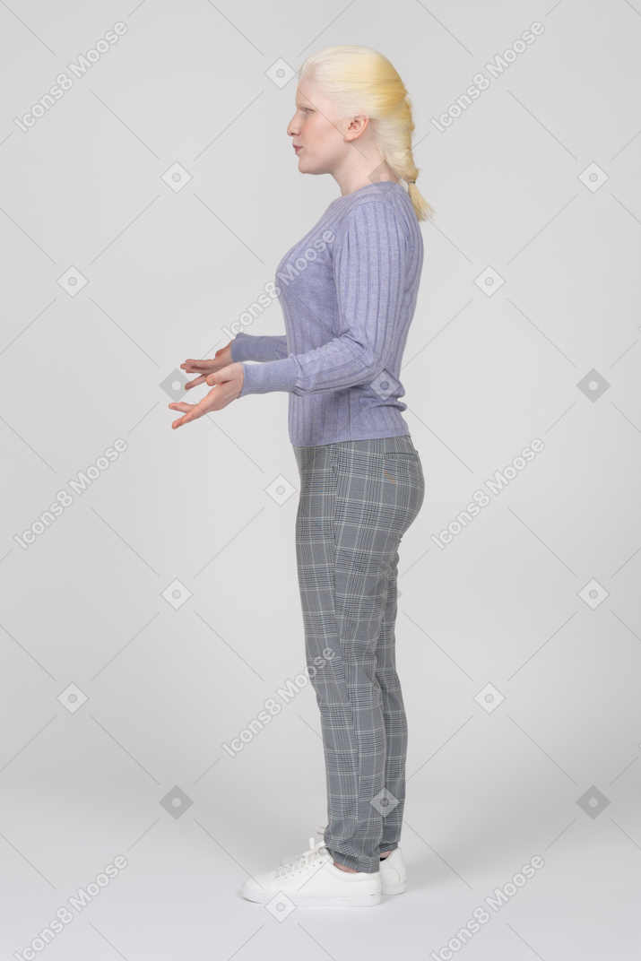 Side view of serious young woman shrugging