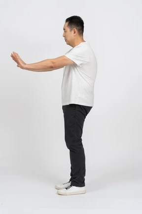 Side view of a man in casual clothes showing stop gesture