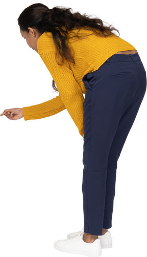 Side view of a girl in casual clothes bending down and pointing with finger