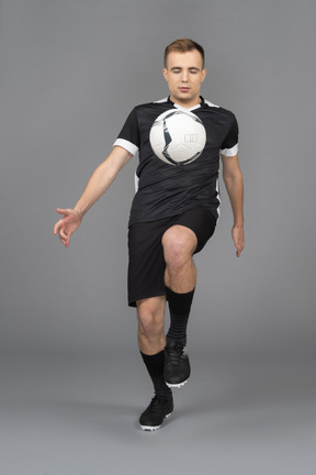 ボールを蹴る男性のサッカー選手の正面図