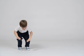 Little boy in casual clothes bending forward