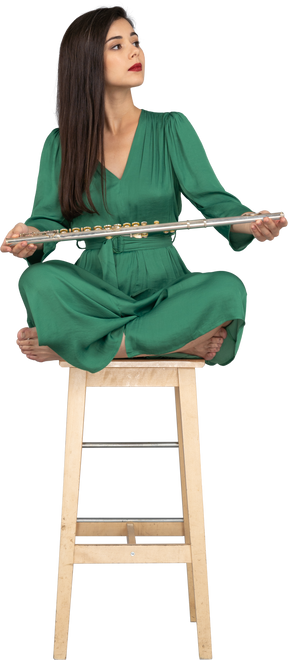 坐在木椅上的年轻女士在膝盖上抱着单簧管的全长