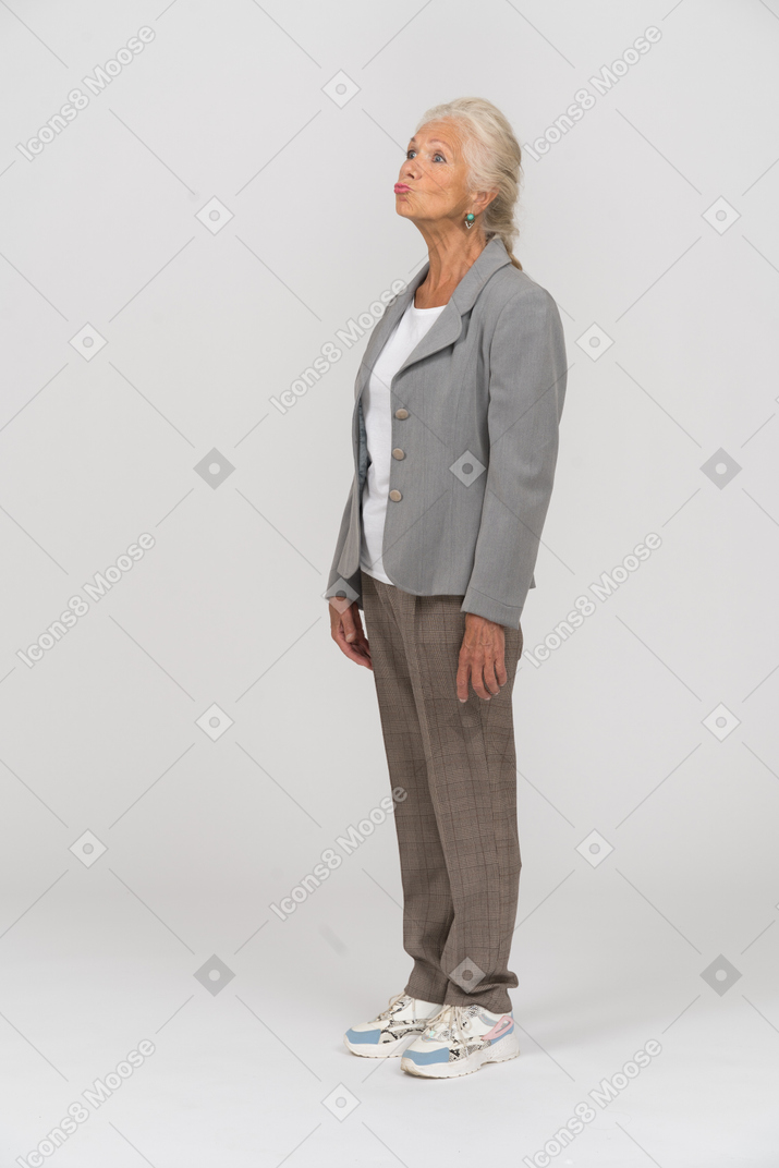 Side view of an old woman in suit blowing a kiss