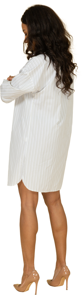 Vista traseira três quartos de uma jovem mulher de pele escura em um vestido branco arregaçando as mangas