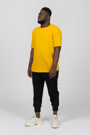 Three-quarter view of a displeased grimacing young dark-skinned man in yellow t-shirt