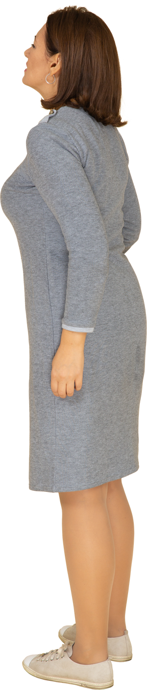 Vista lateral de uma mulher de vestido cinza sofrendo de dor de estômago