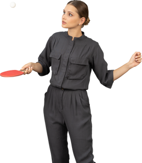 Front view of young woman in a jumpsuit playing table tennis