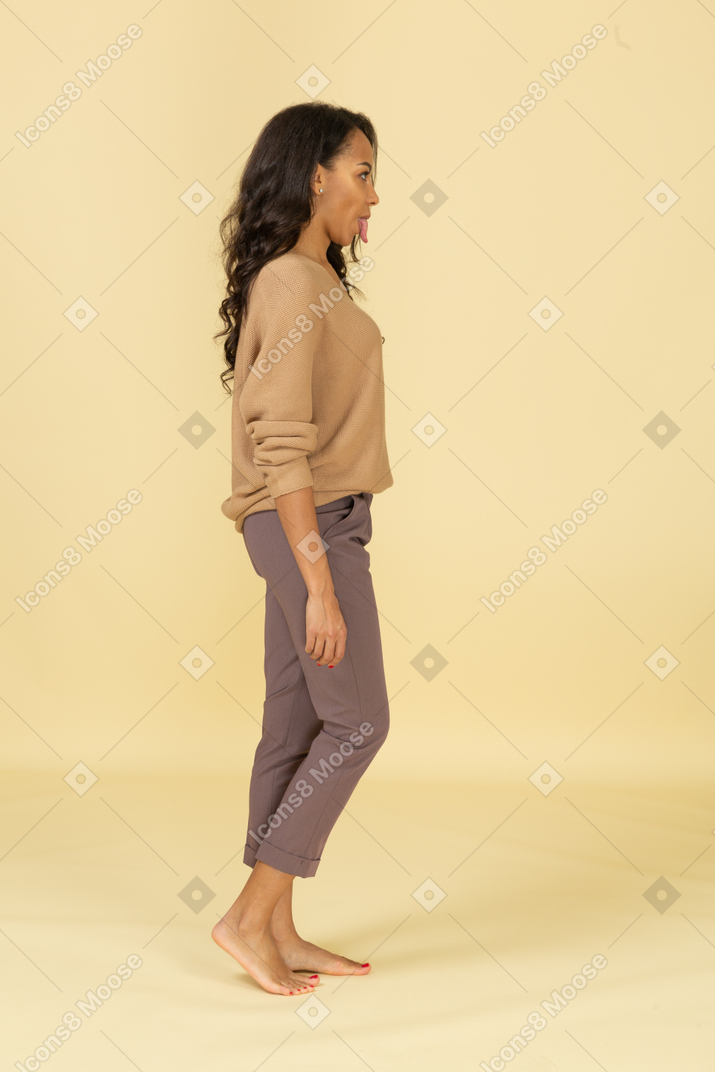 Side view of a young female in casual clothes showing tongue