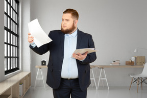 A man in a suit is holding a piece of paper