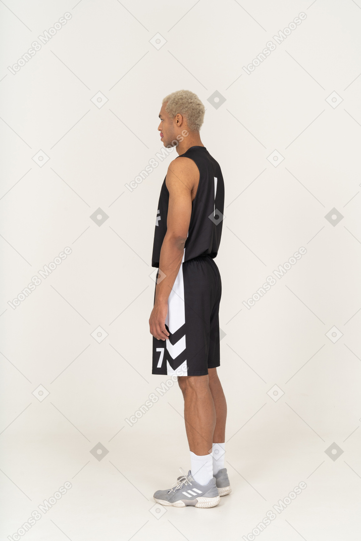 Vista posteriore di tre quarti di un giovane giocatore di basket che si lecca le labbra