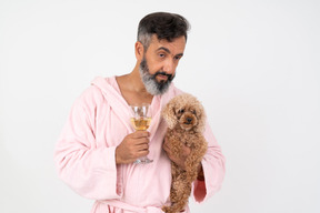 Homem maduro, segurando um copo de vinho e um cachorrinho