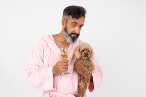 Homme d'âge mûr tenant un verre de vin et un chiot