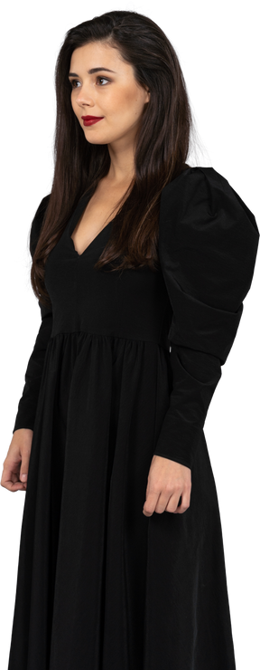 Vue de trois quarts d'une jeune femme souriante dans une robe noire immobile