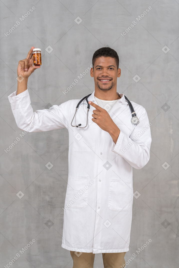 Médico alegre apontando para o frasco de comprimidos