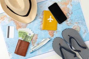 A flat lay picture of all the necessary things for a modern summer trip, including a credit card, summer accessories and a smartphone
