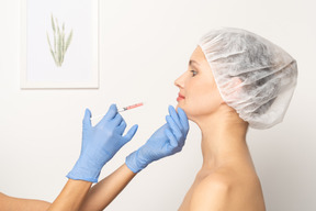 Vista lateral de una mujer que recibe una inyección de botox