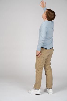 Side view of a boy with raised arm looking up