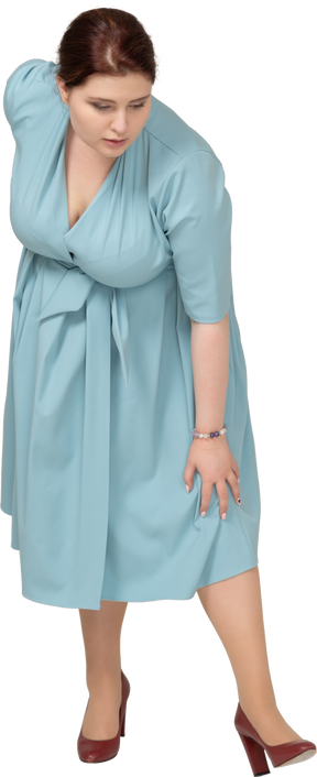 Vista frontal de uma mulher de vestido azul curvando-se