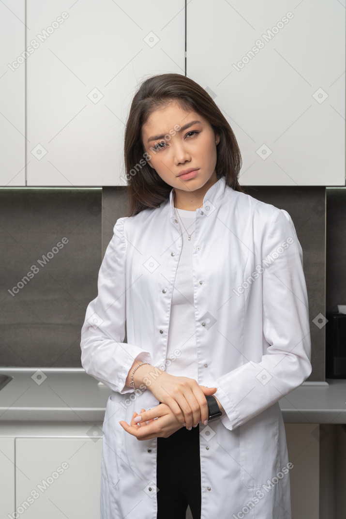 Front view of a suspicious female doctor touching hands