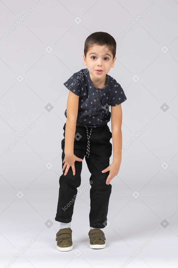 Front view of an impessed boy bending down and looking at camera