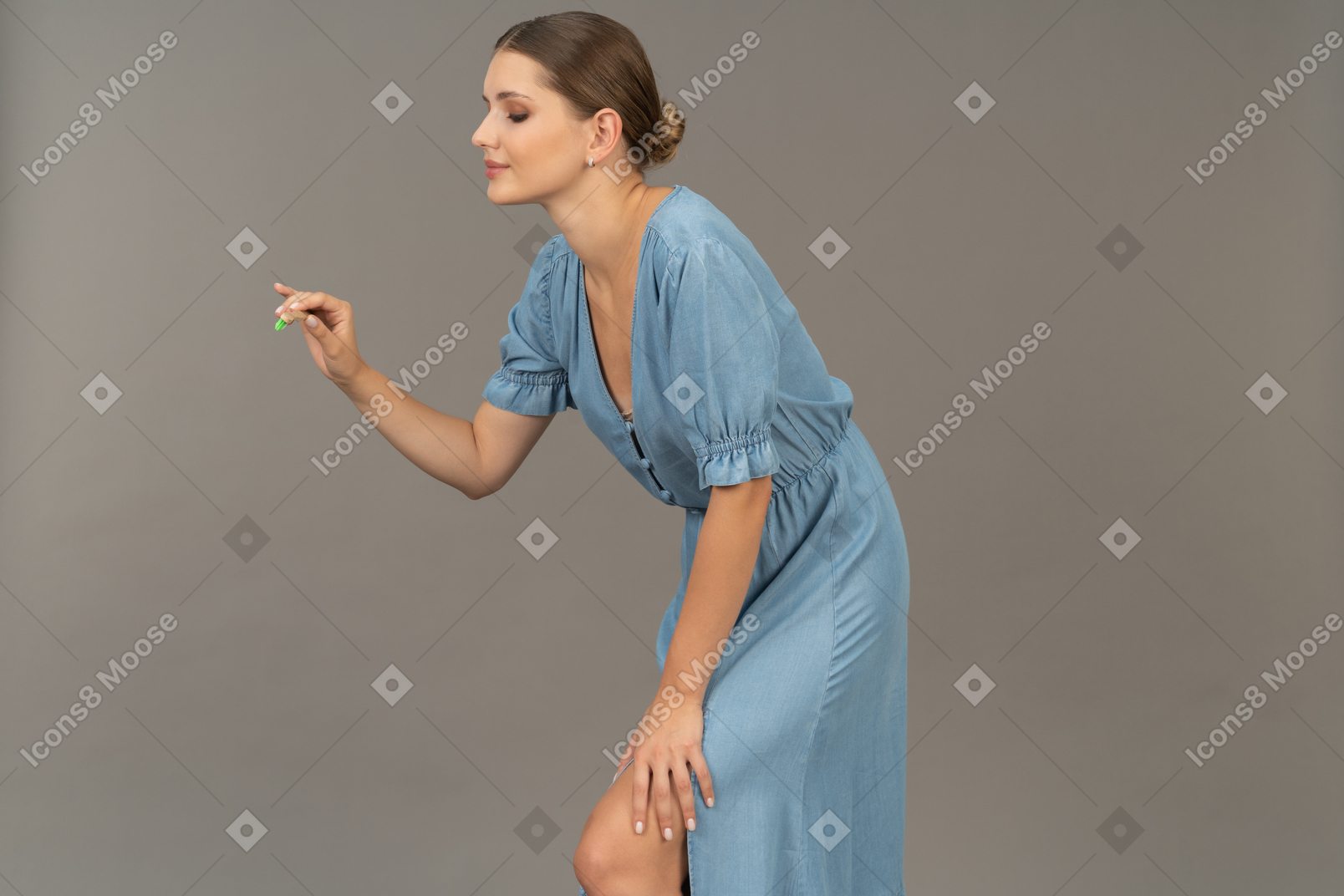 歯ブラシを保持し、前かがみに青いドレスを着た若い女性の側面図