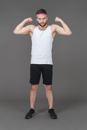 Спортивный молодой человек показывает свое мускулистое телосложение