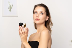 Three-quarter view of a sensual young woman holding a bottle of perfume