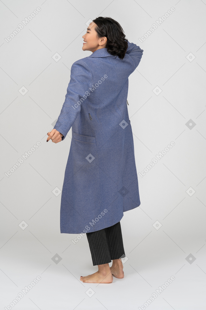 Vista posteriore di una donna allegra in cappotto