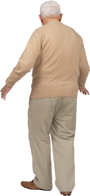Вид сзади на старика в повседневной одежде, стоящего с протянутыми руками