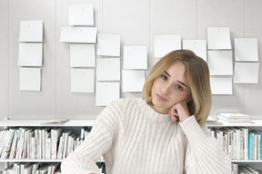 A woman sitting at a desk in front of a wall of paper